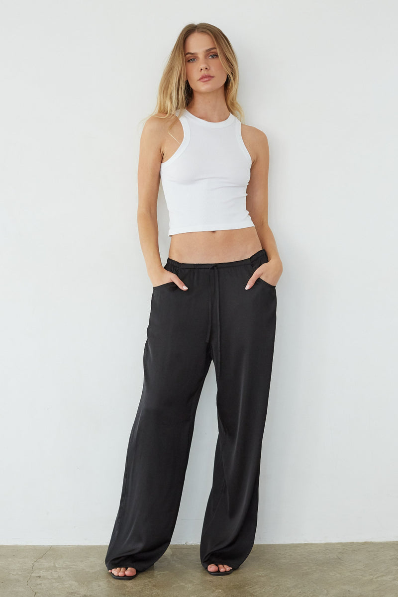 black-image | front-image | Woman wearing a white tank top and black wide-leg pants against a plain background