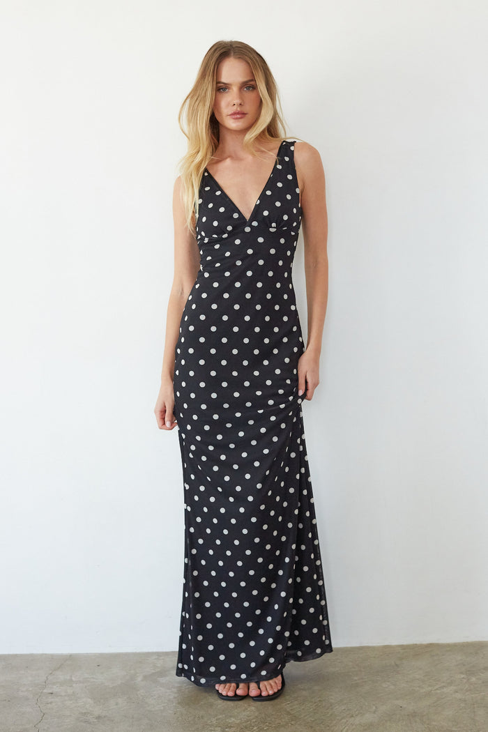 black-image | Woman wearing a black dress with white polka dots against a plain background