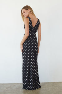 Woman wearing a black dress with white polka dots against a plain background