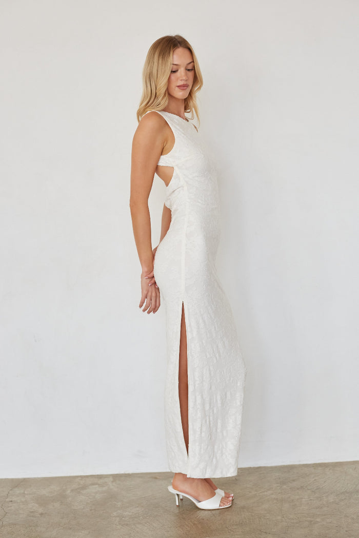 Woman wearing a white dress with cut-out design on a plain background