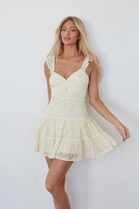 yellow-image | Woman wearing a white lace dress against a plain background