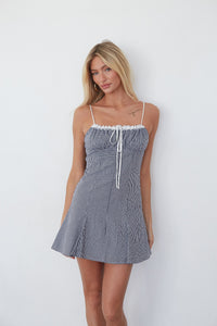 blue-image | Woman wearing a blue and white checkered dress against a white background