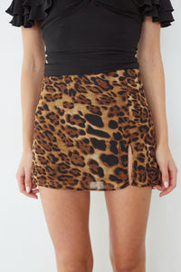 Person wearing a black top and leopard print skirt on a white background