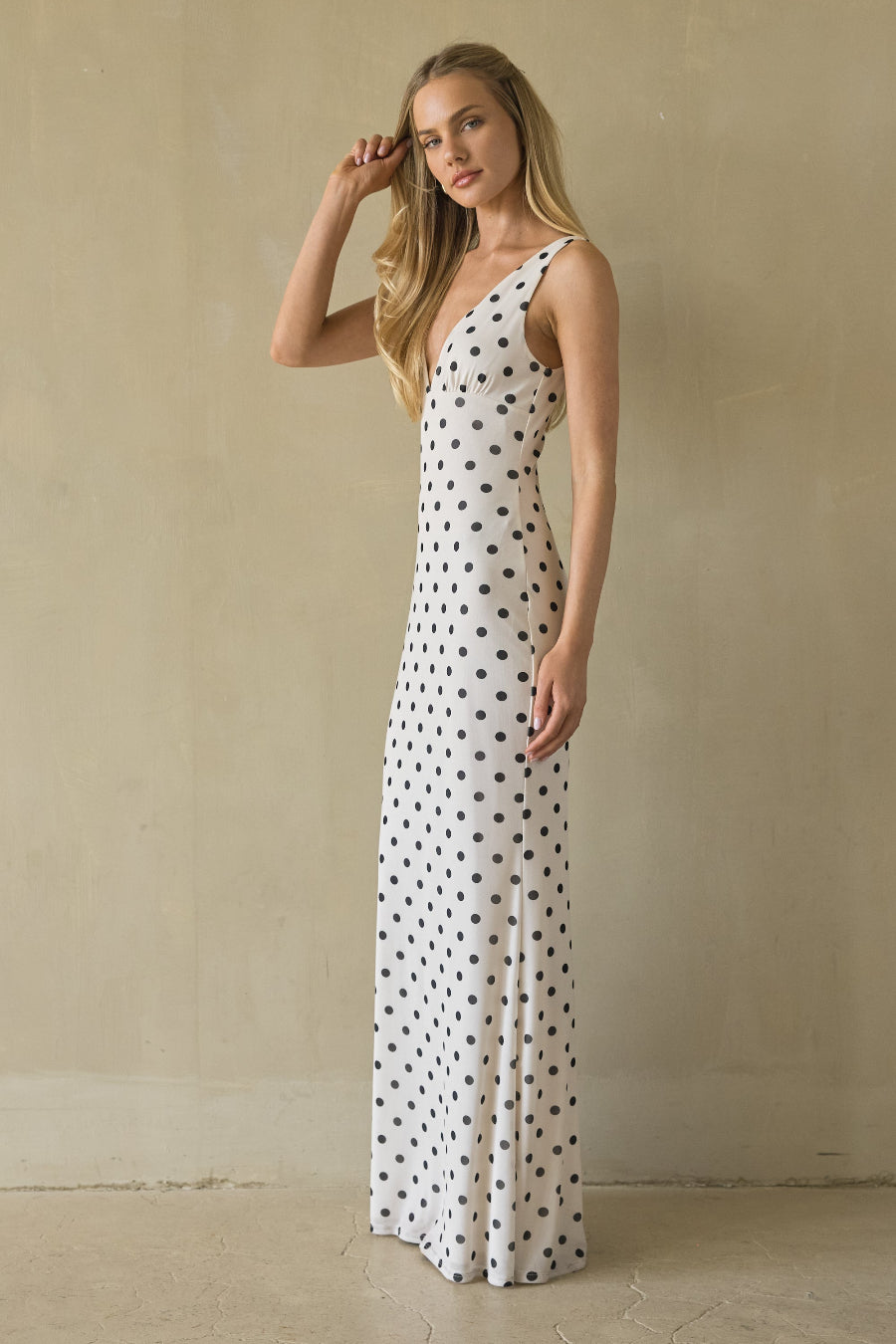 Woman wearing a polka dot dress against a beige wall