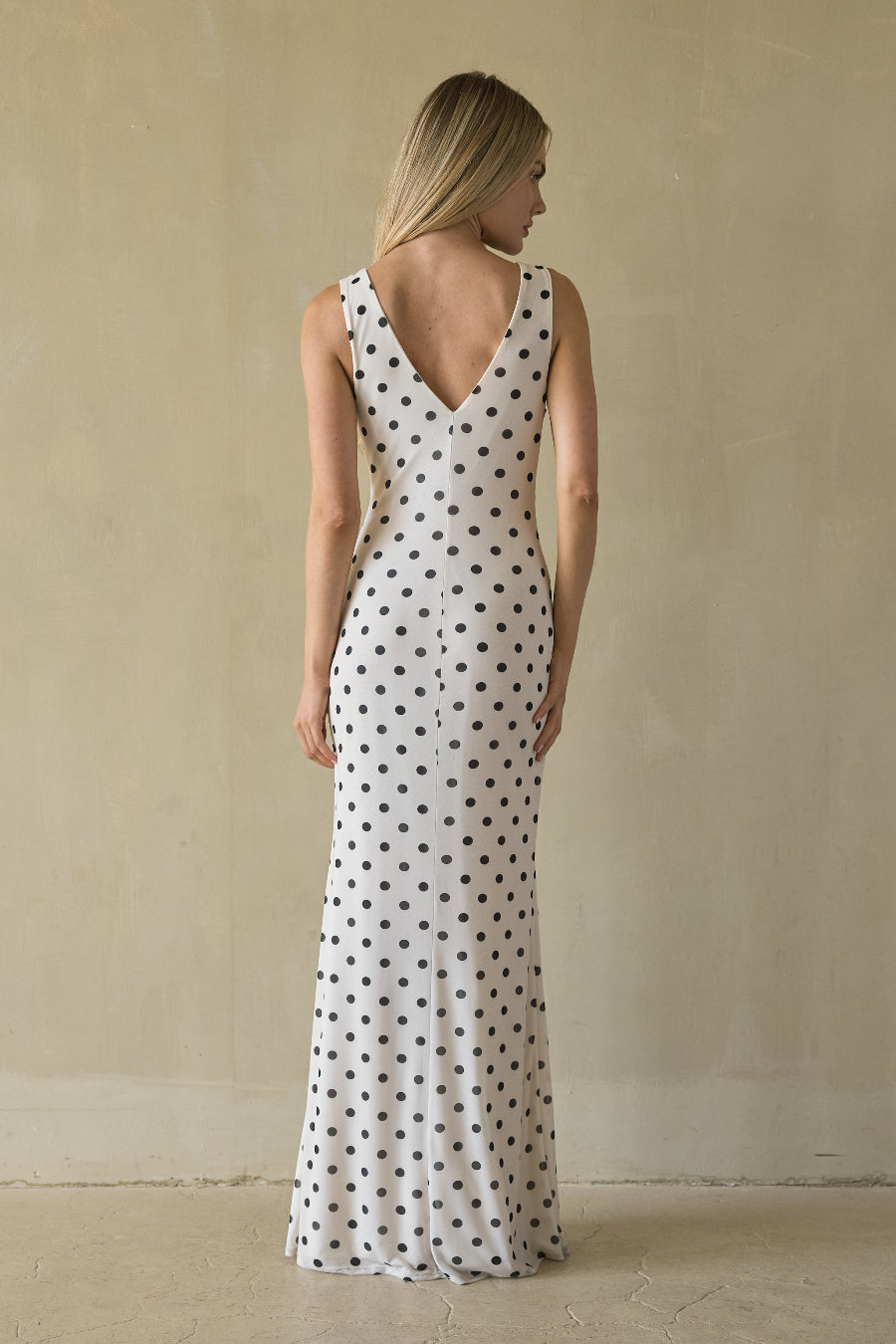 Woman wearing a long polka dot dress against a plain background