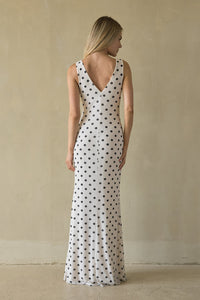 Woman wearing a long polka dot dress against a plain background