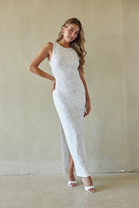 Woman wearing a white lace dress with a high slit in a minimalistic setting