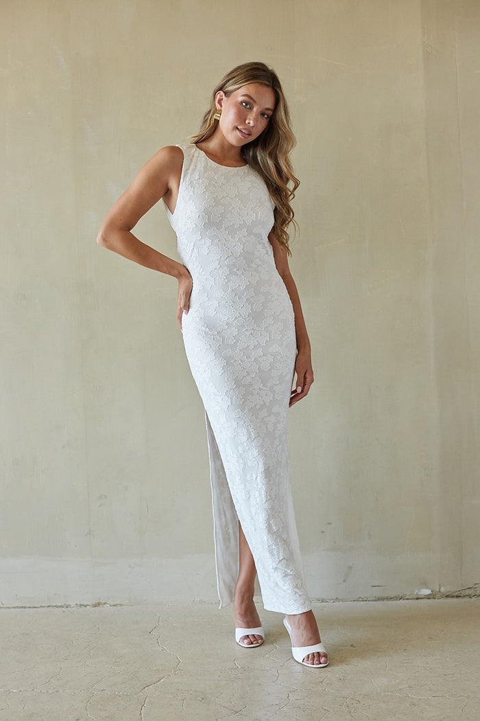 Woman wearing a white lace dress with a high slit in a minimalistic setting