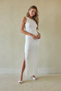 Woman wearing a white lace dress against a plain background