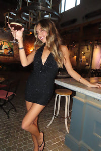 front-image | girl in a black embellished mini dress standing at the bar with a drink