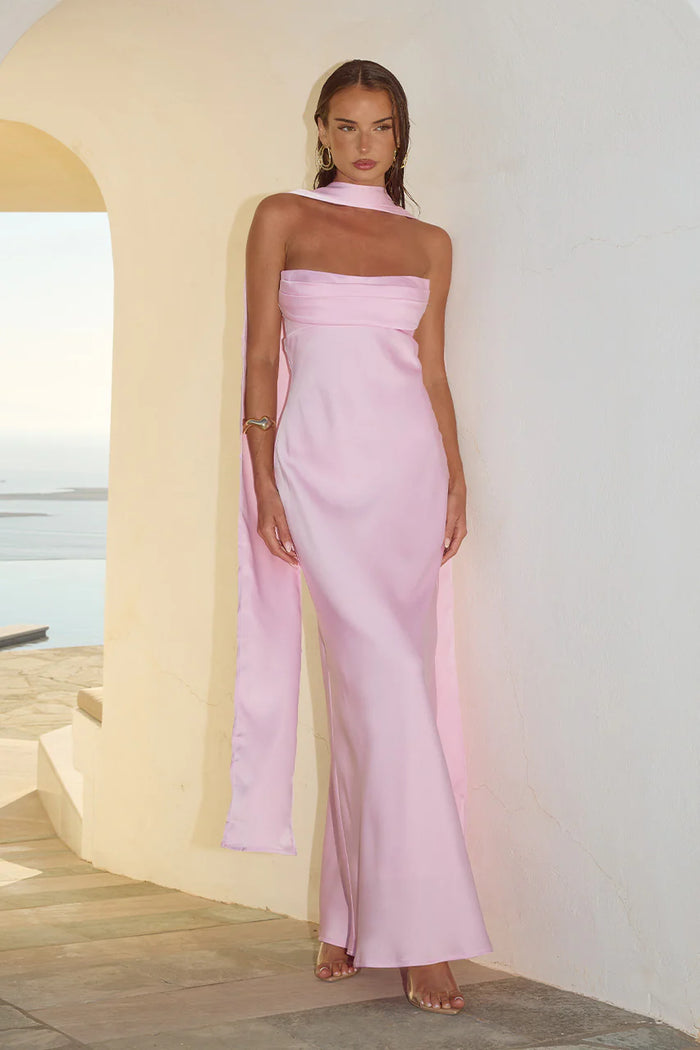 pink-image | Woman wearing a pink strapless jumpsuit standing against a white wall with a scenic background.