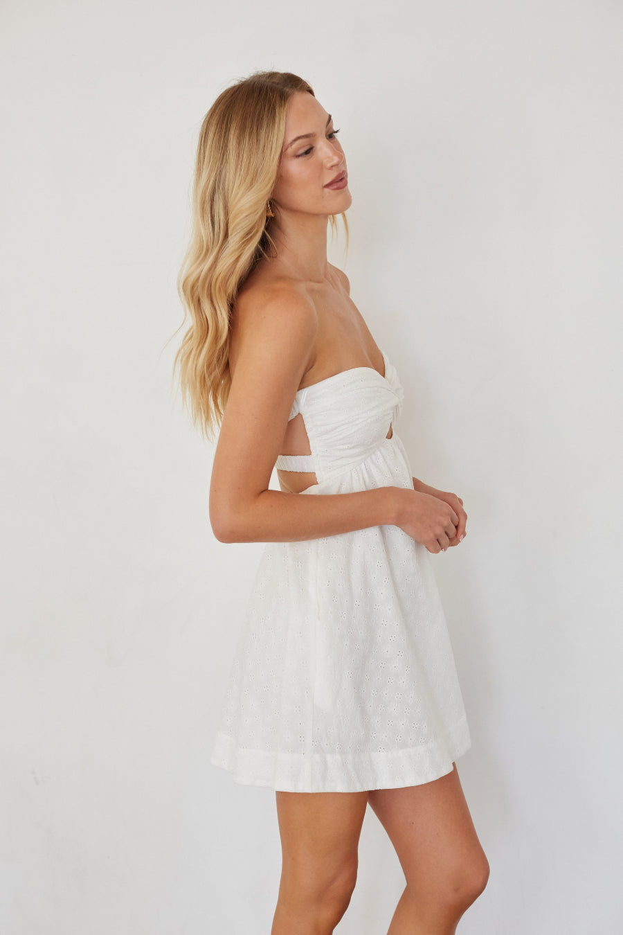 Woman wearing a white strapless dress against a plain background