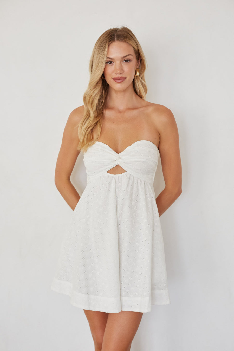 Woman wearing a white strapless dress against a plain background