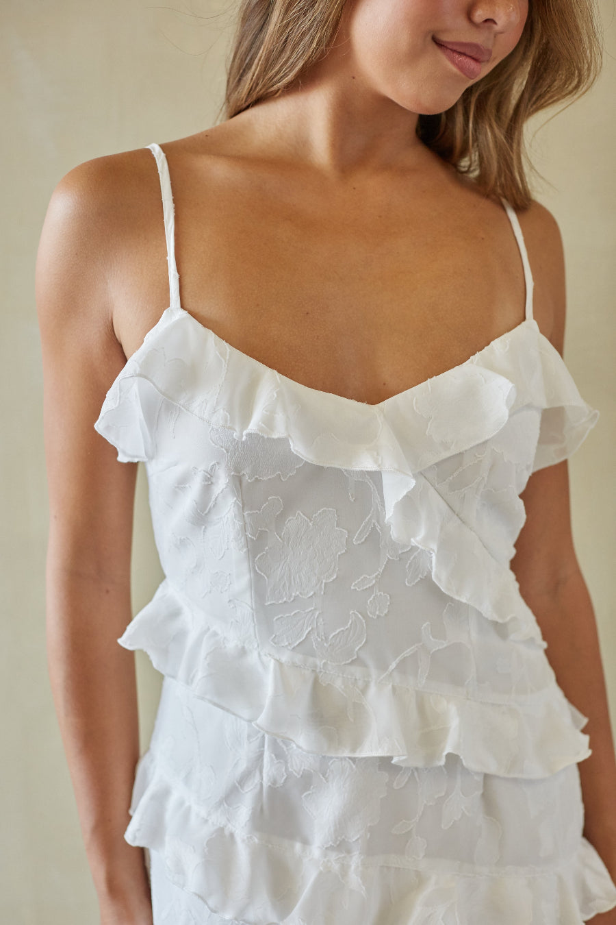White lace dress with ruffled layers worn by a person against a neutral background
