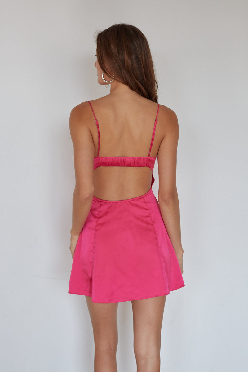 Woman wearing a pink bikini and skirt set against a plain background