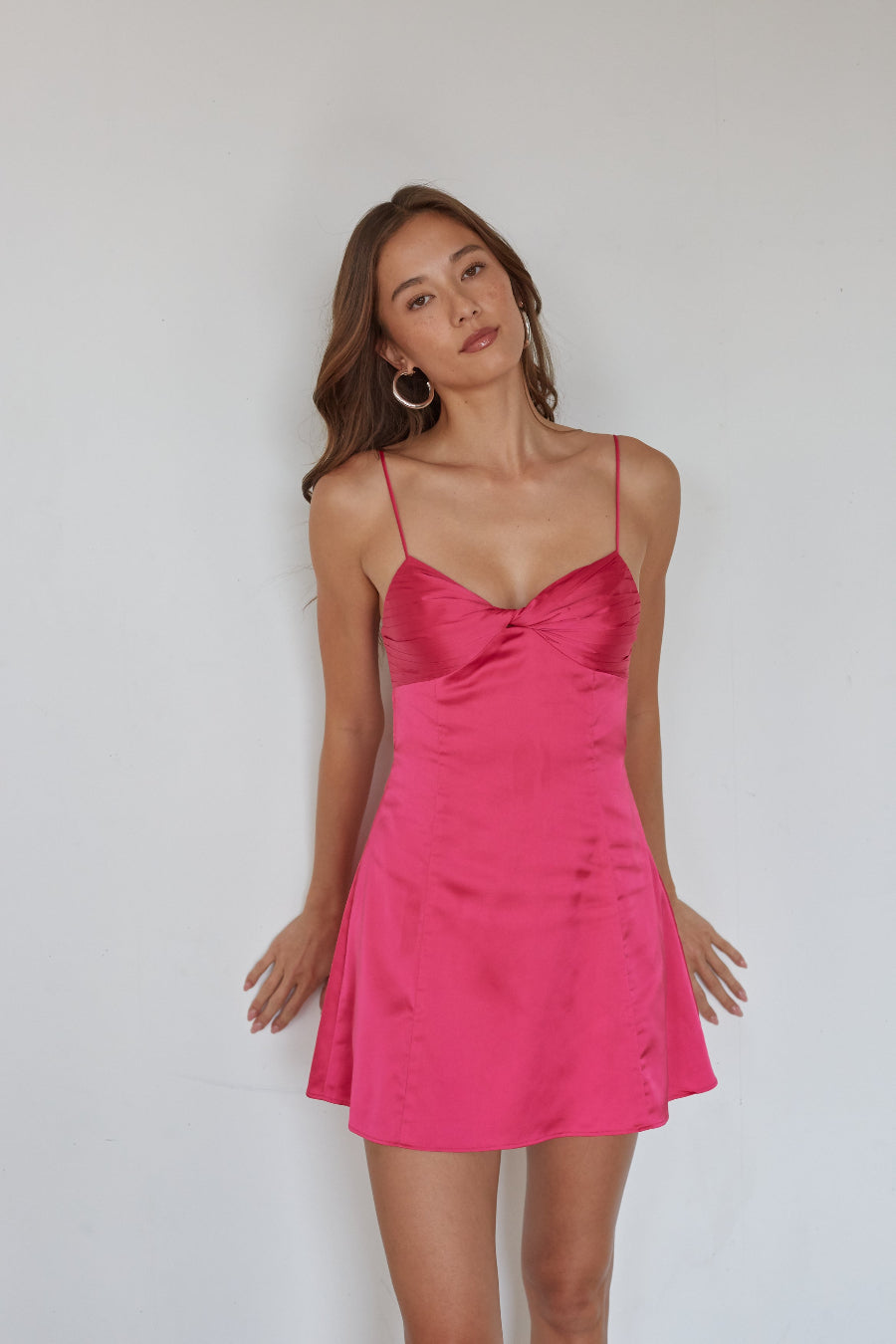 Woman wearing a pink satin dress against a plain background
