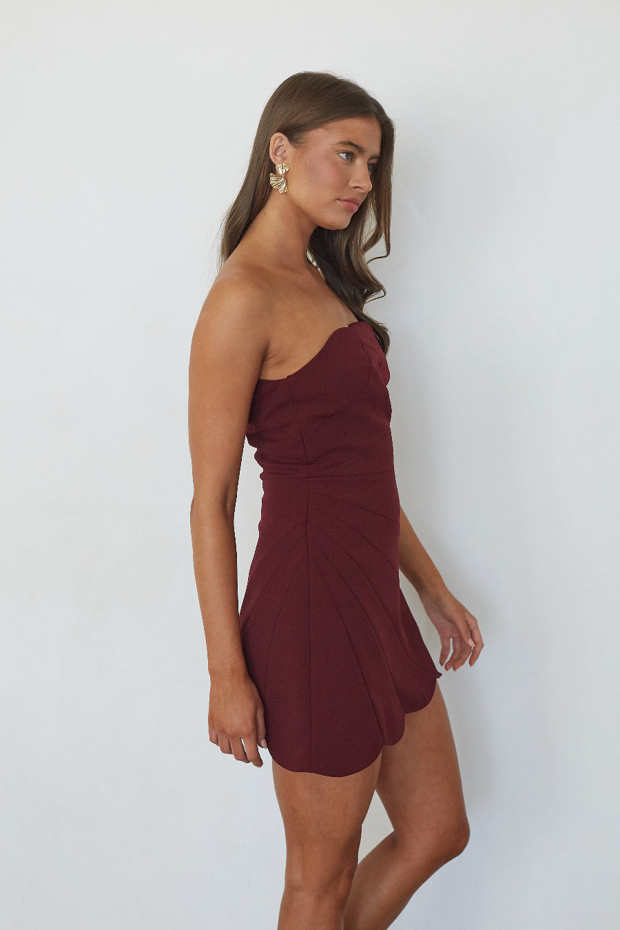 Burgundy strapless scalloped trim mini dress, side profile view showing fit and flare silhouette