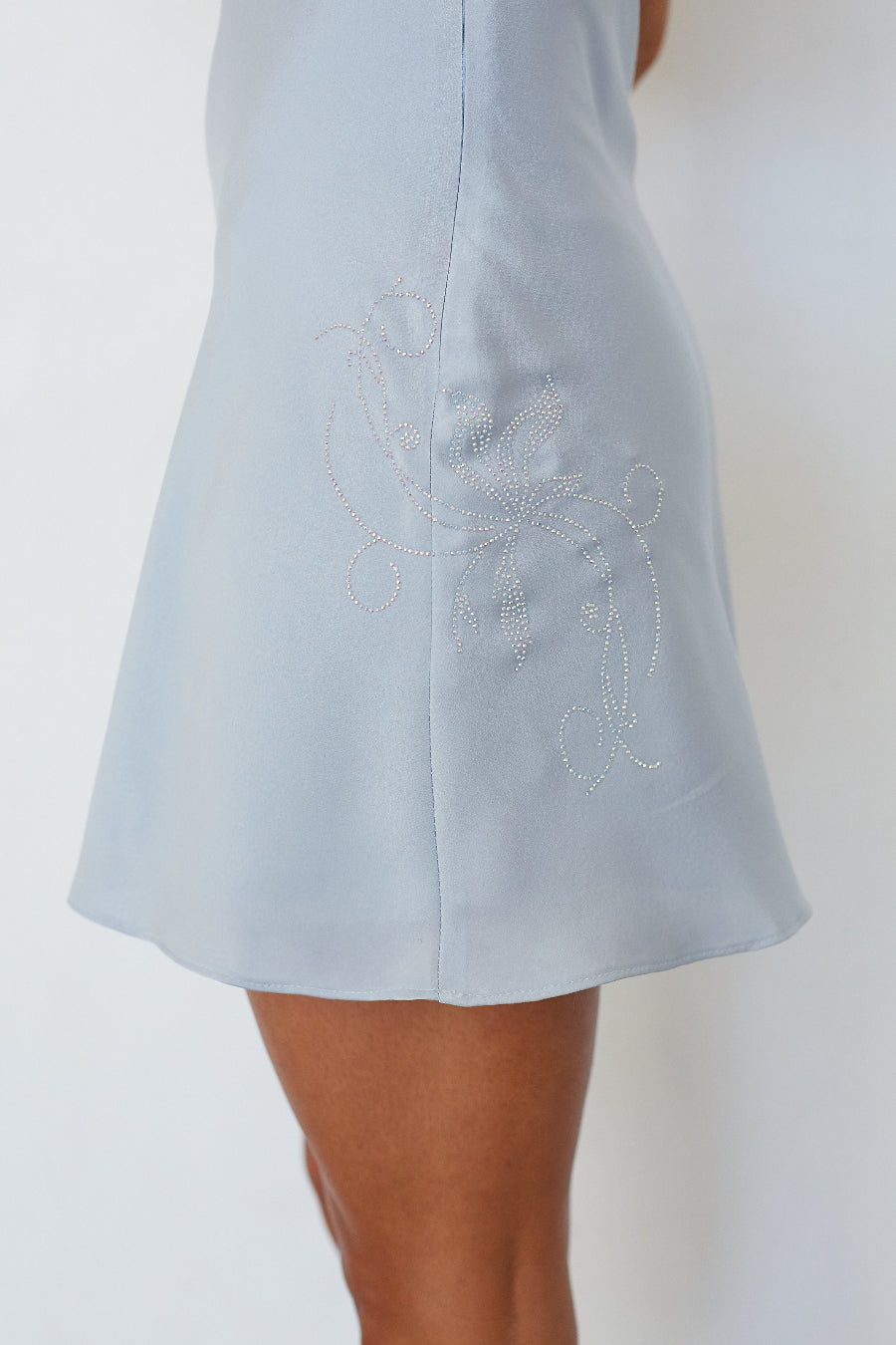 Close-up of rhinestone floral embellishment on light blue satin mini dress