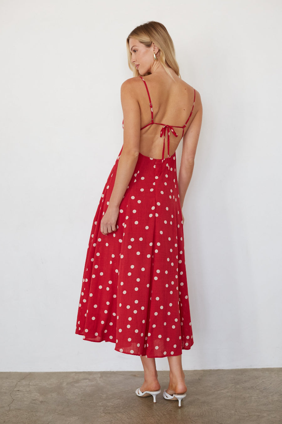 Woman wearing a red polka dot dress against a white background