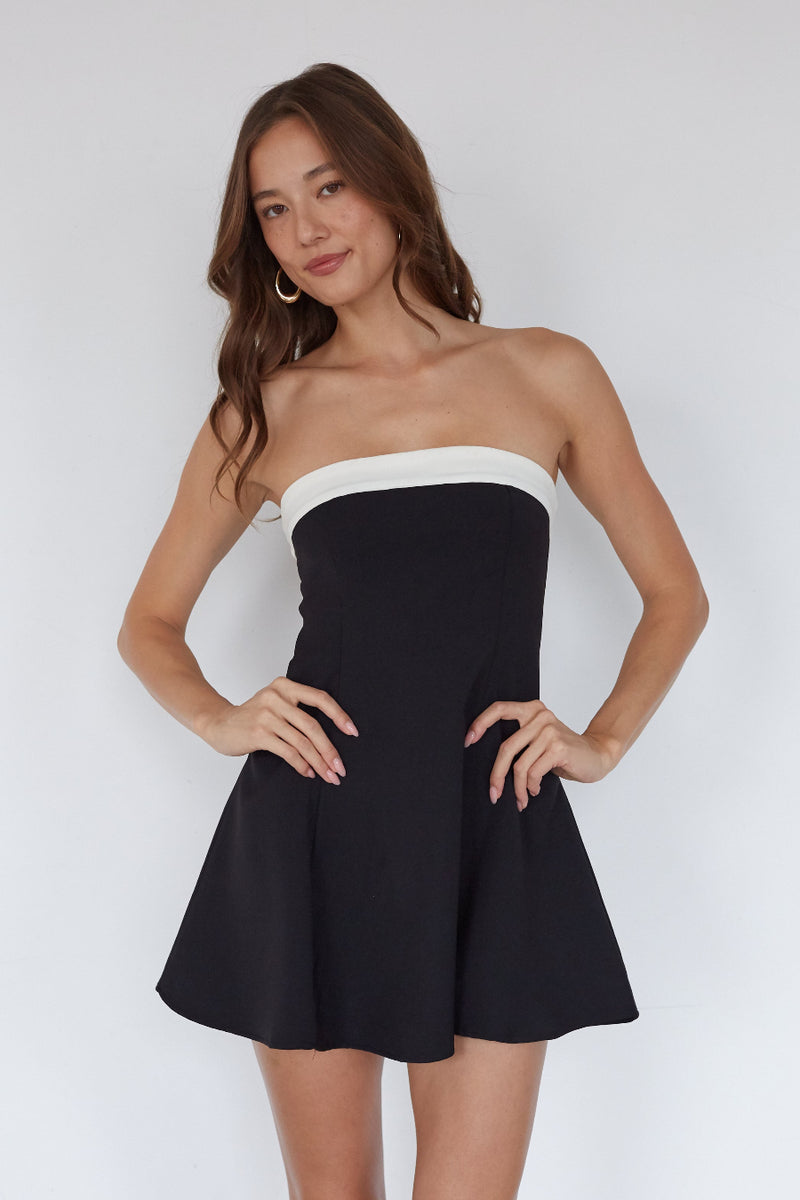 black-image | Woman wearing a black and white strapless dress against a plain background