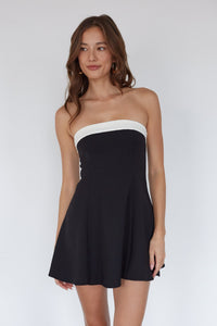 Woman wearing a black and white strapless dress on a white background