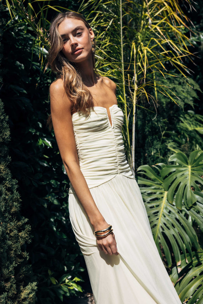 yellow-image | Woman in a strapless yellow dress standing among tropical plants