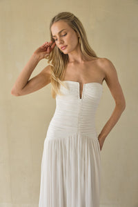 Woman wearing a strapless white dress against a beige background