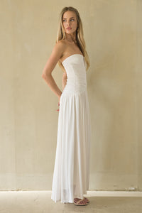 Woman wearing a strapless white dress against a plain background