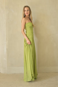 Woman wearing a strapless green gown against a plain background