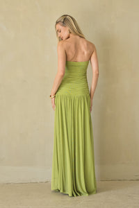 Woman wearing a strapless green dress against a beige wall.