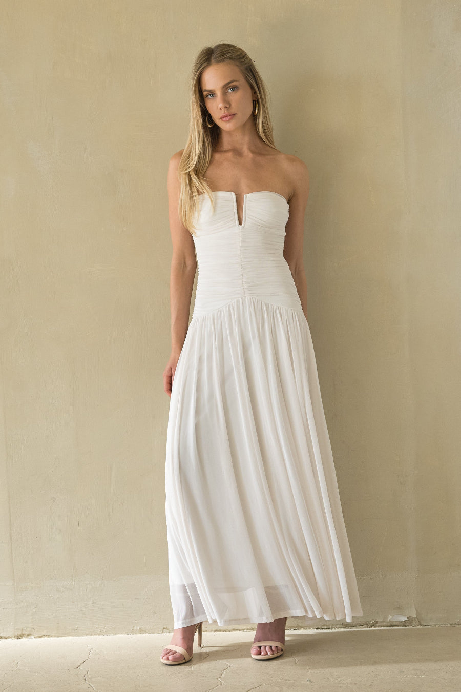 white-image | Woman wearing a strapless white dress against a plain wall.