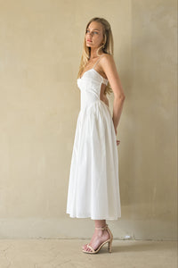 Woman wearing a white dress against a beige wall