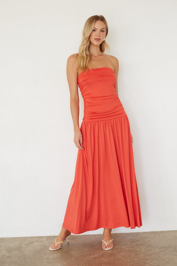 Woman wearing a strapless coral dress against a white background