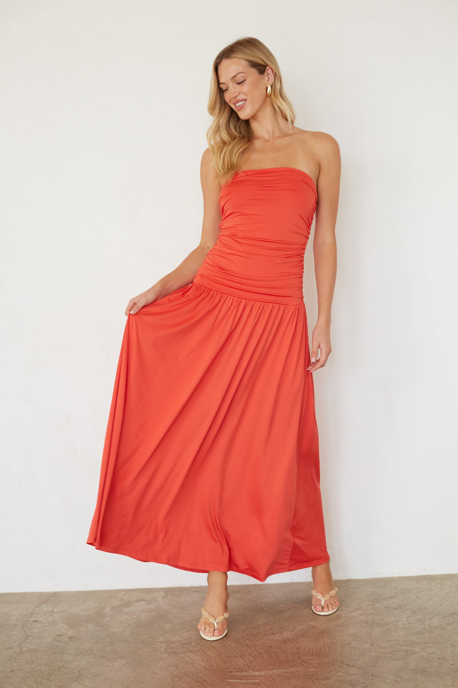 Woman wearing a strapless coral dress against a white background