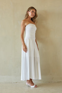 Woman wearing a white strapless dress against a plain background