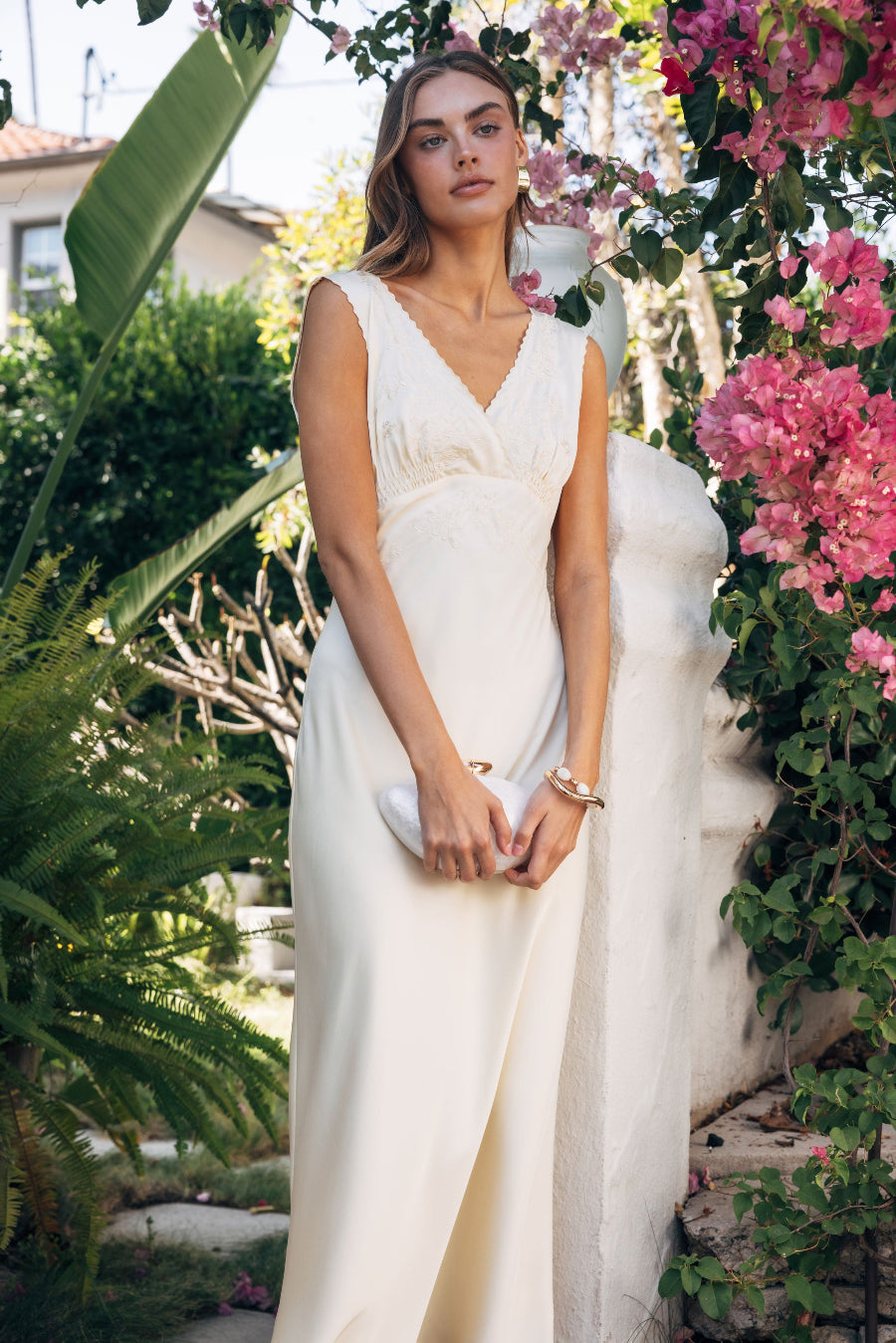 Woman in a white dress standing among flowers and greenery