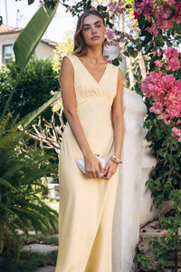 Woman in a white dress standing among flowers and greenery