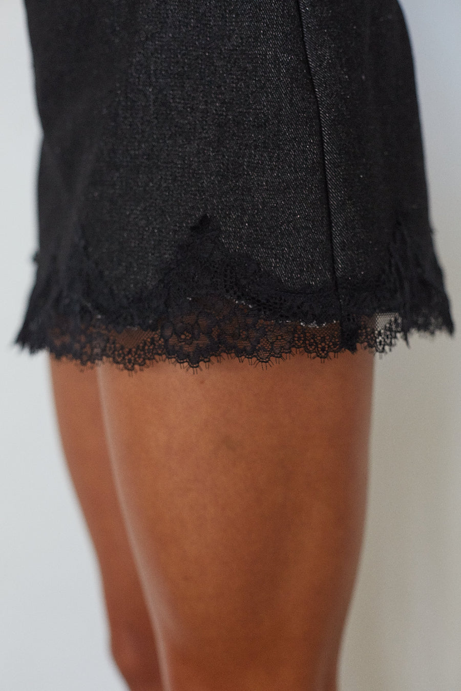 Close-up of scalloped lace trim detail on black denim mini skort