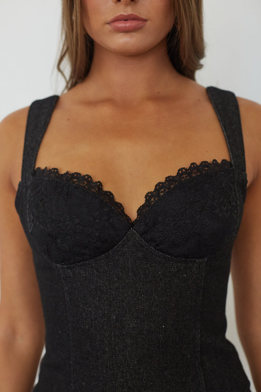 Close-up of lace trim detail on black denim bustier top