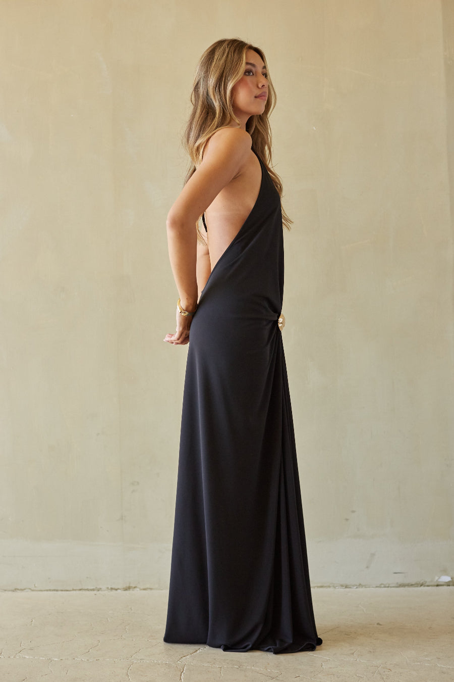 Woman wearing a black halter neck dress against a plain background