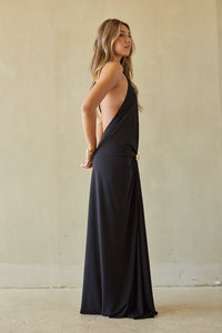 Woman wearing a black halter neck dress against a plain background