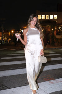 Woman in a white outfit crossing a street at night.