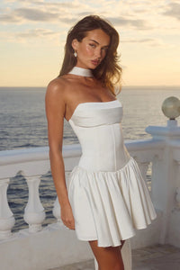 Woman in a white dress standing on a balcony with ocean view