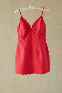 red-image | Red dress on a hanger against a beige wall