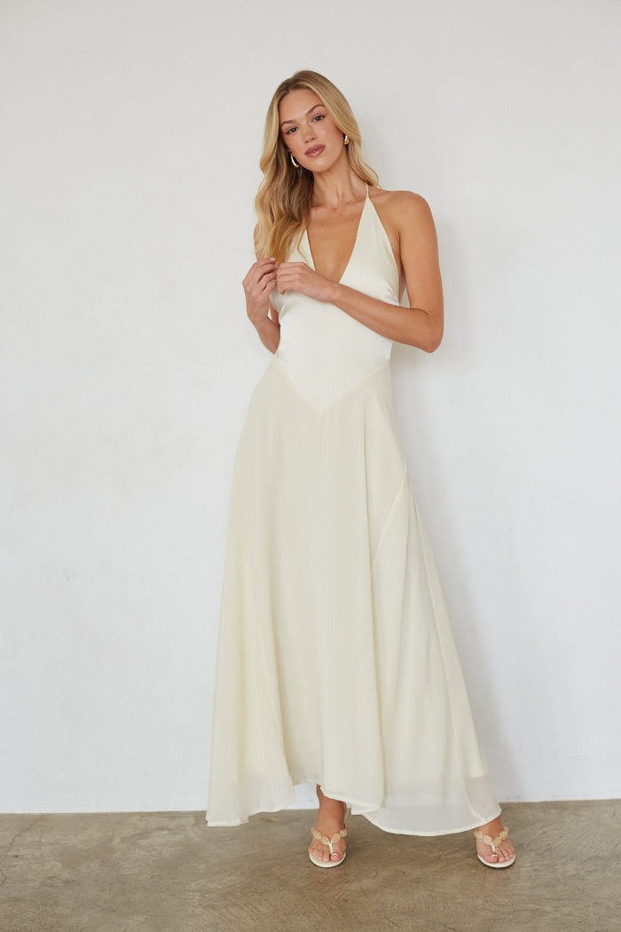 Woman wearing a white halter neck dress against a plain background