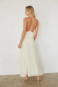 Woman wearing a white dress with thin straps against a plain background