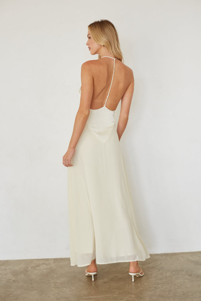 Woman wearing a white dress with thin straps against a plain background