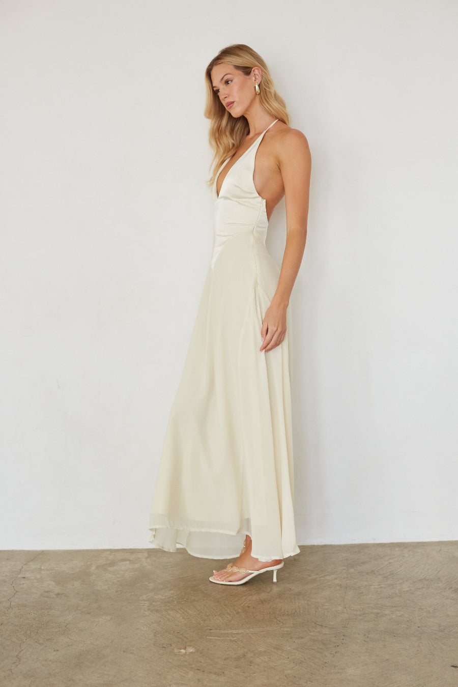 Woman wearing a long, light-colored dress against a plain background