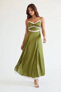 A woman modeling a floor-length olive green satin dress with white lace trim at the bust, waist, and hem, photographed against a plain white studio background.