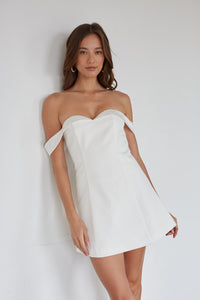 Woman wearing a white strapless dress against a plain background